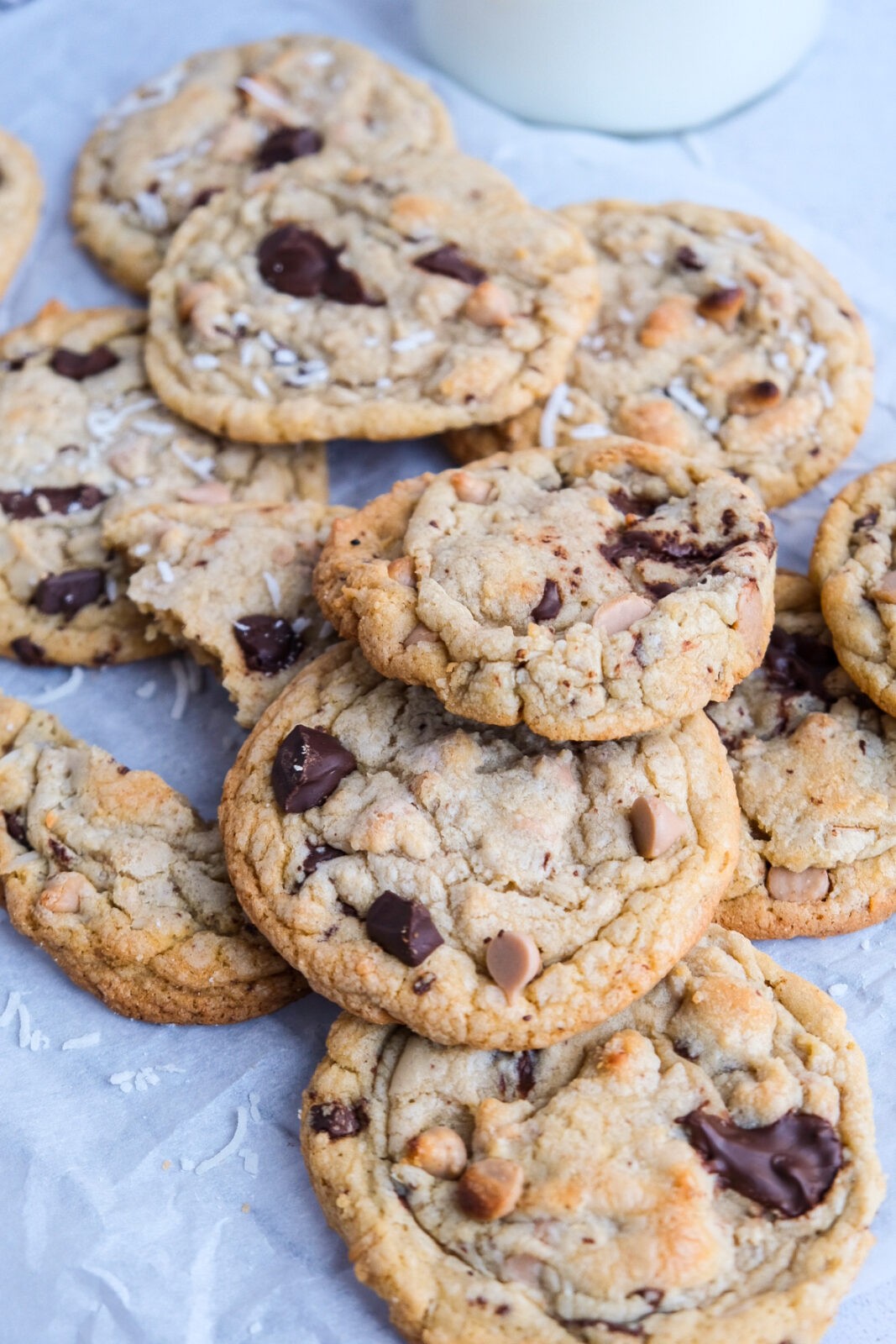 A picture of several baked coconut chocolate caramel cookies on a layer of parchment paper and on top of a cooling rack